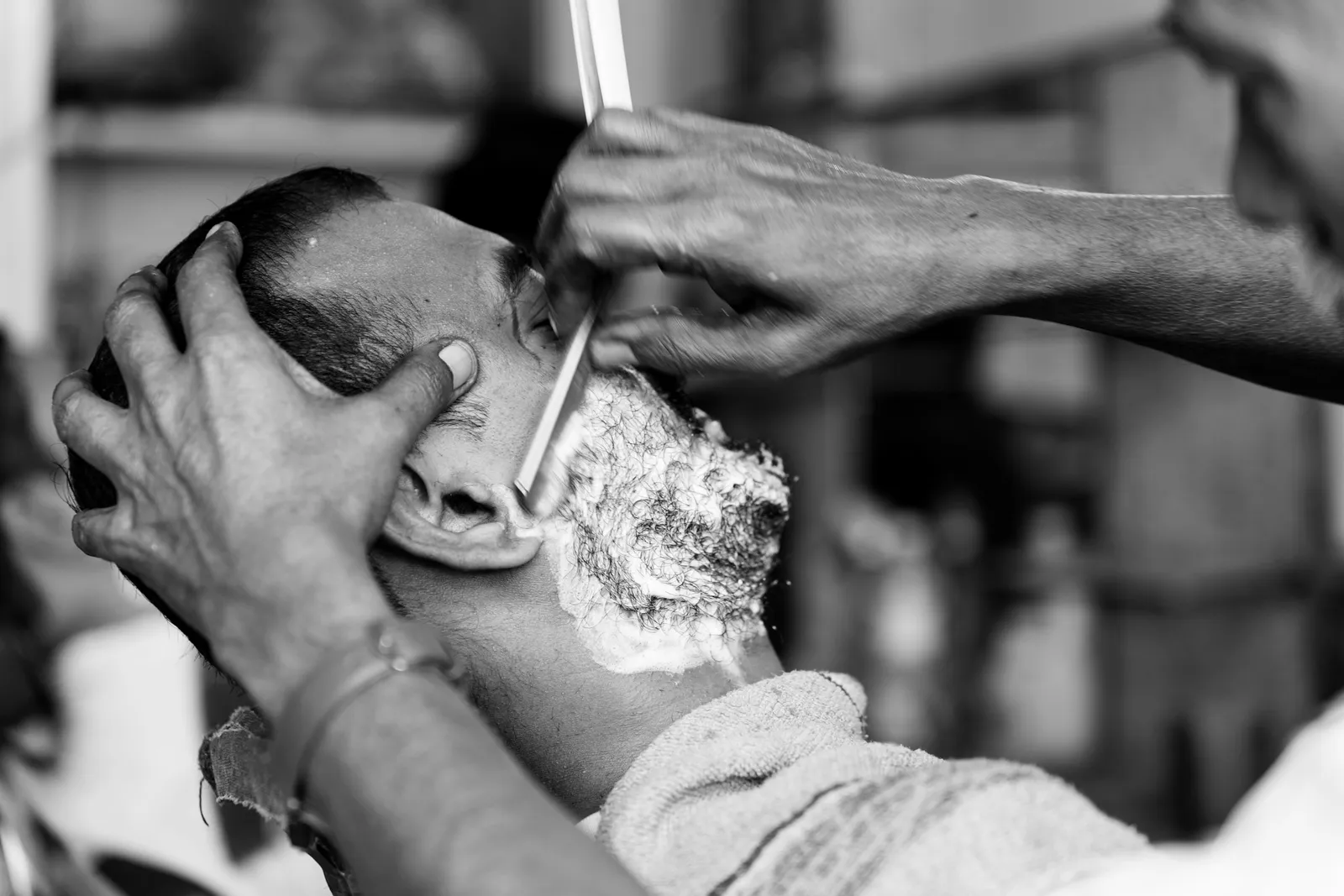 A black and white photo of a straight razor shave with foam