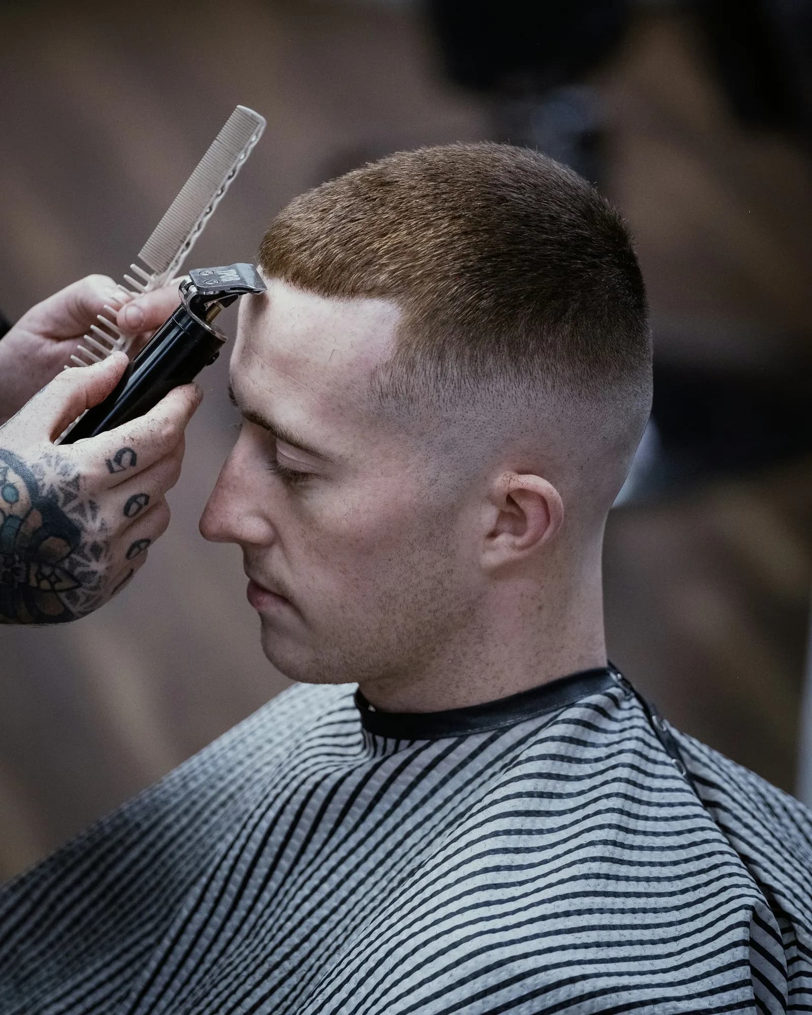 A barber lines up a short crop with a trimmer and a comb
