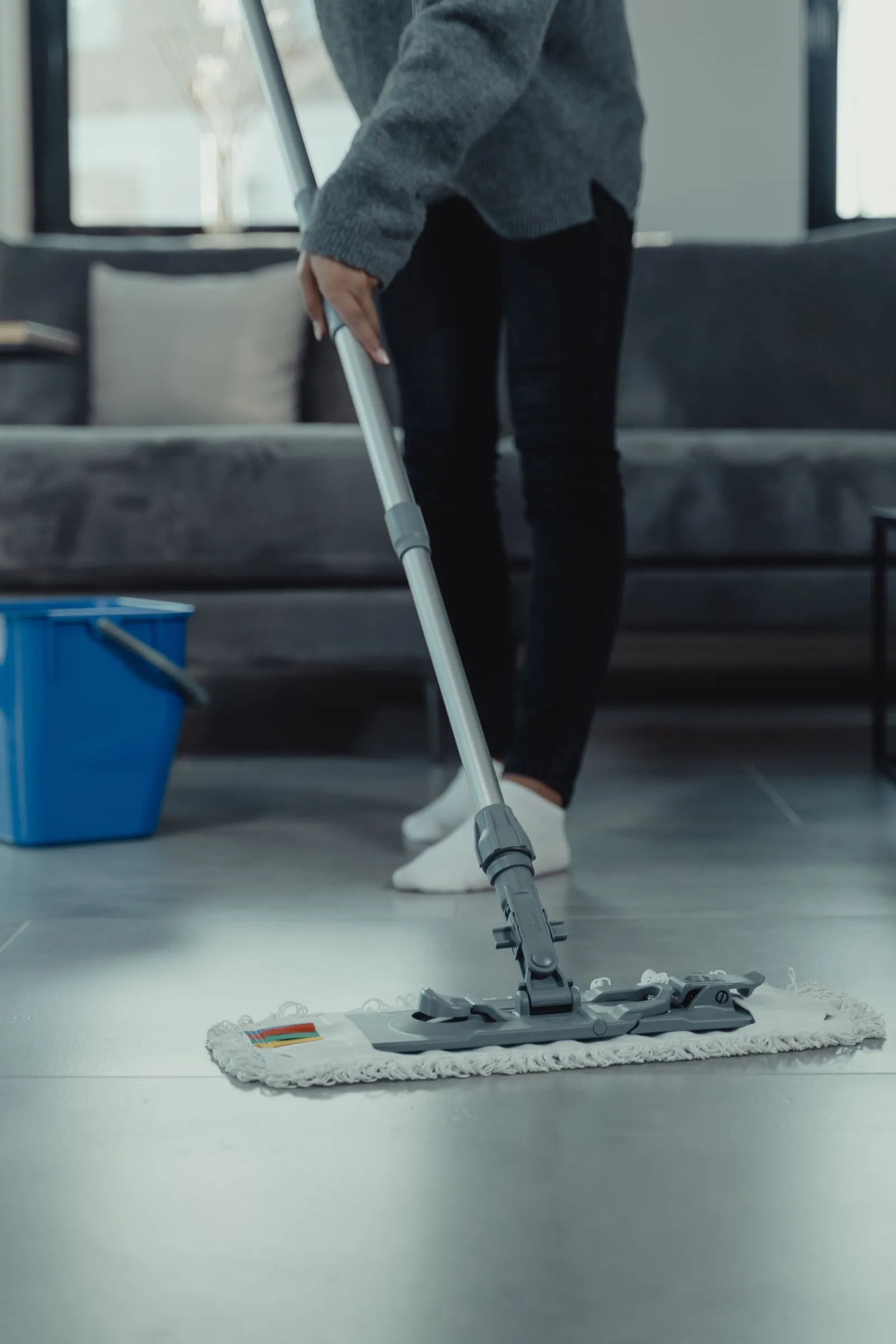 Someone mops a tile floor in a living room