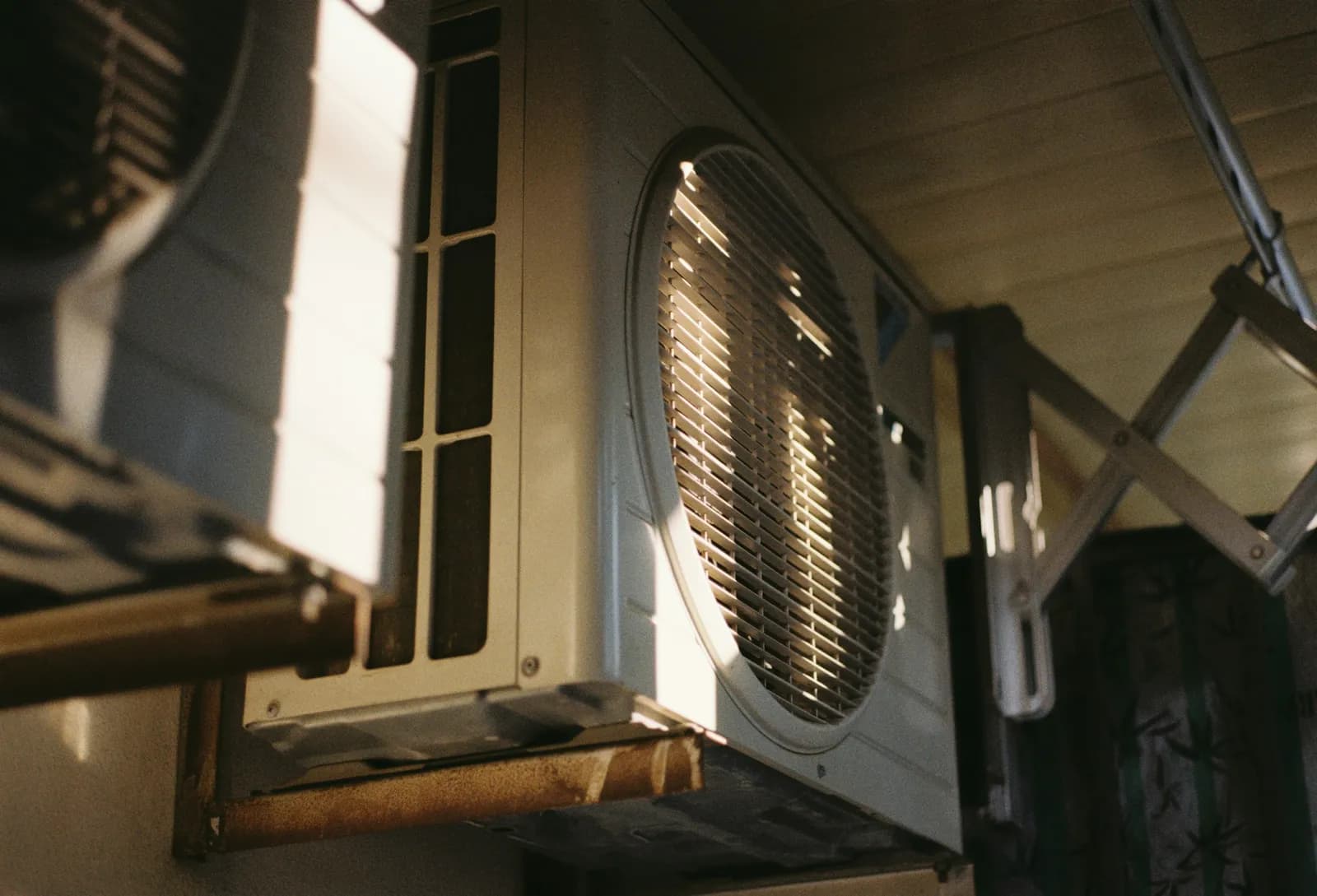 An outdoor AC unit on a wall in late sun