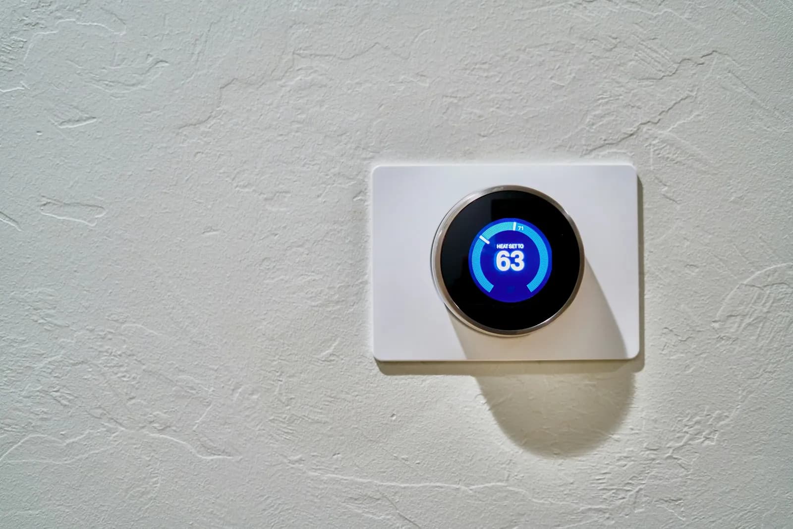A round thermostat on a white wall