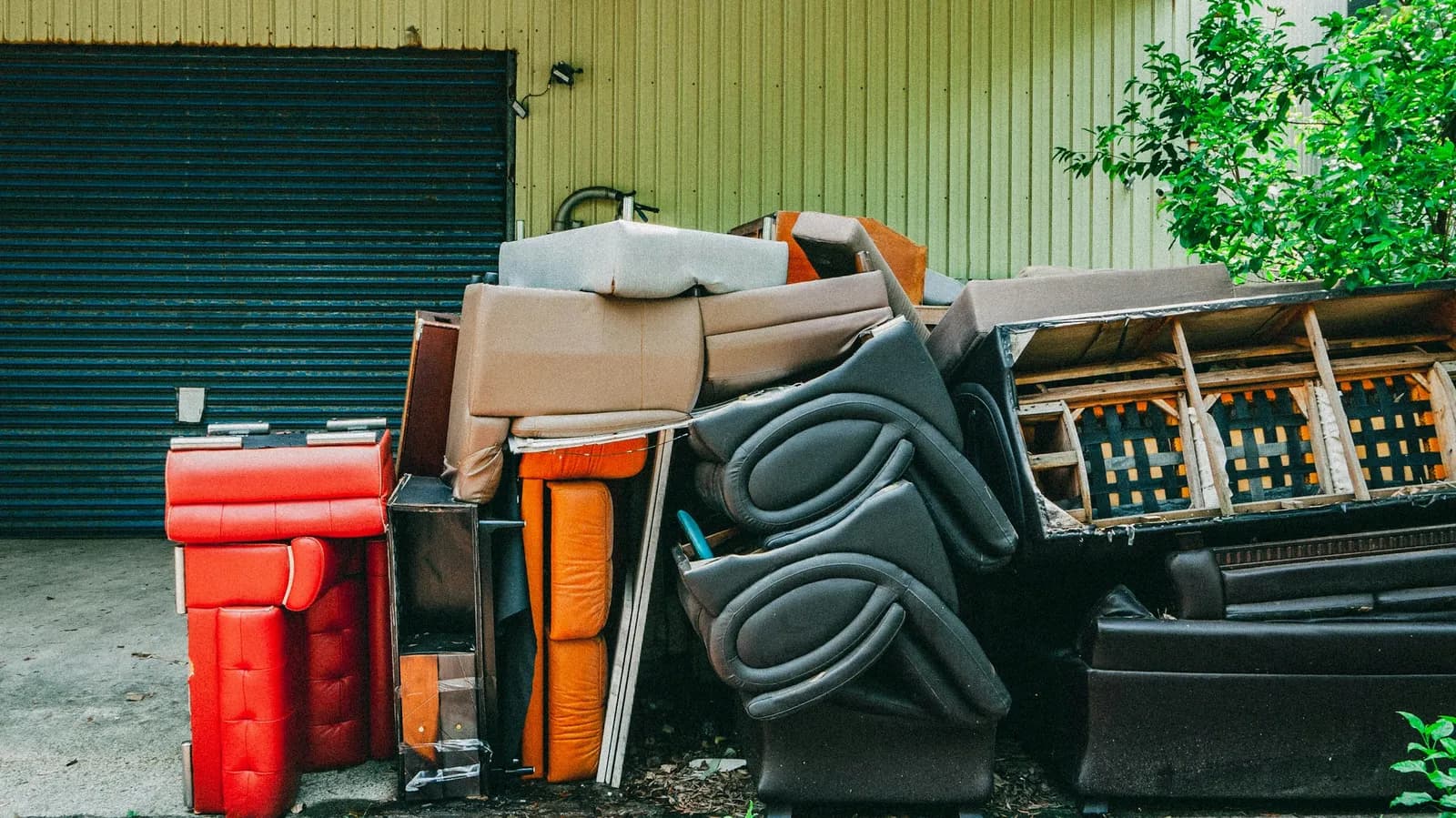 Old couches and chairs piled up by a garage door