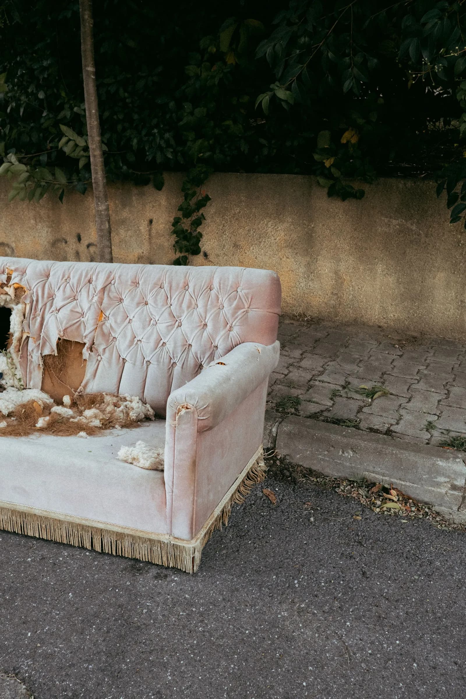 A worn pink couch left by the curb