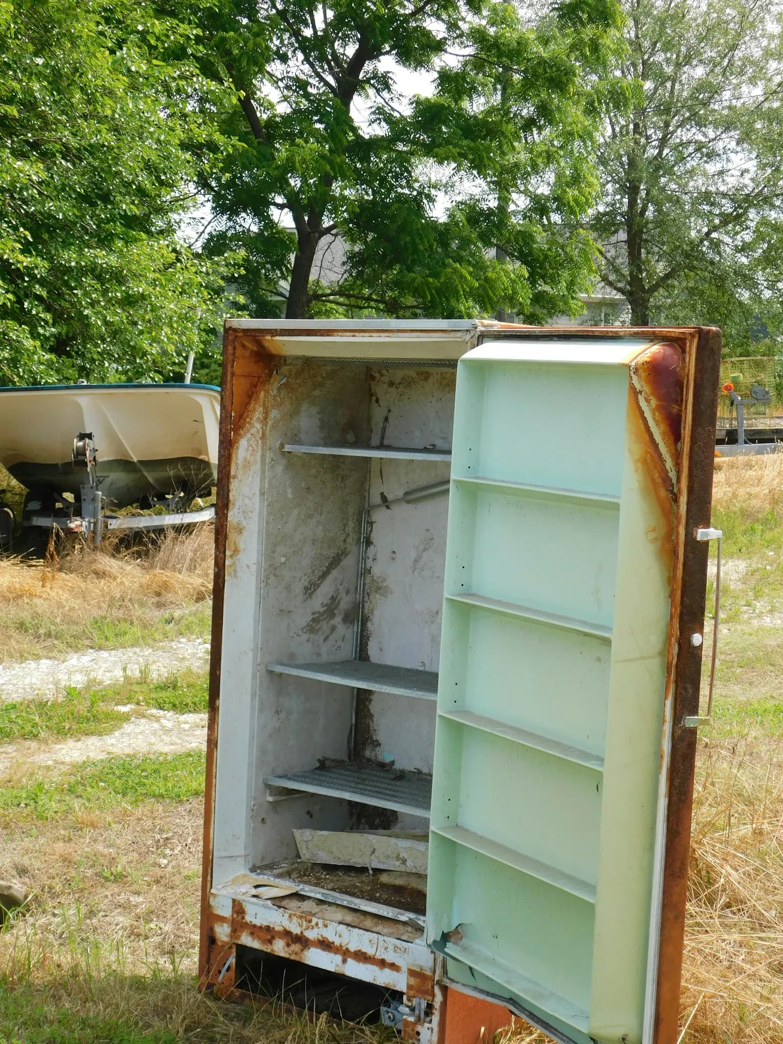An old rusty fridge out in the grass