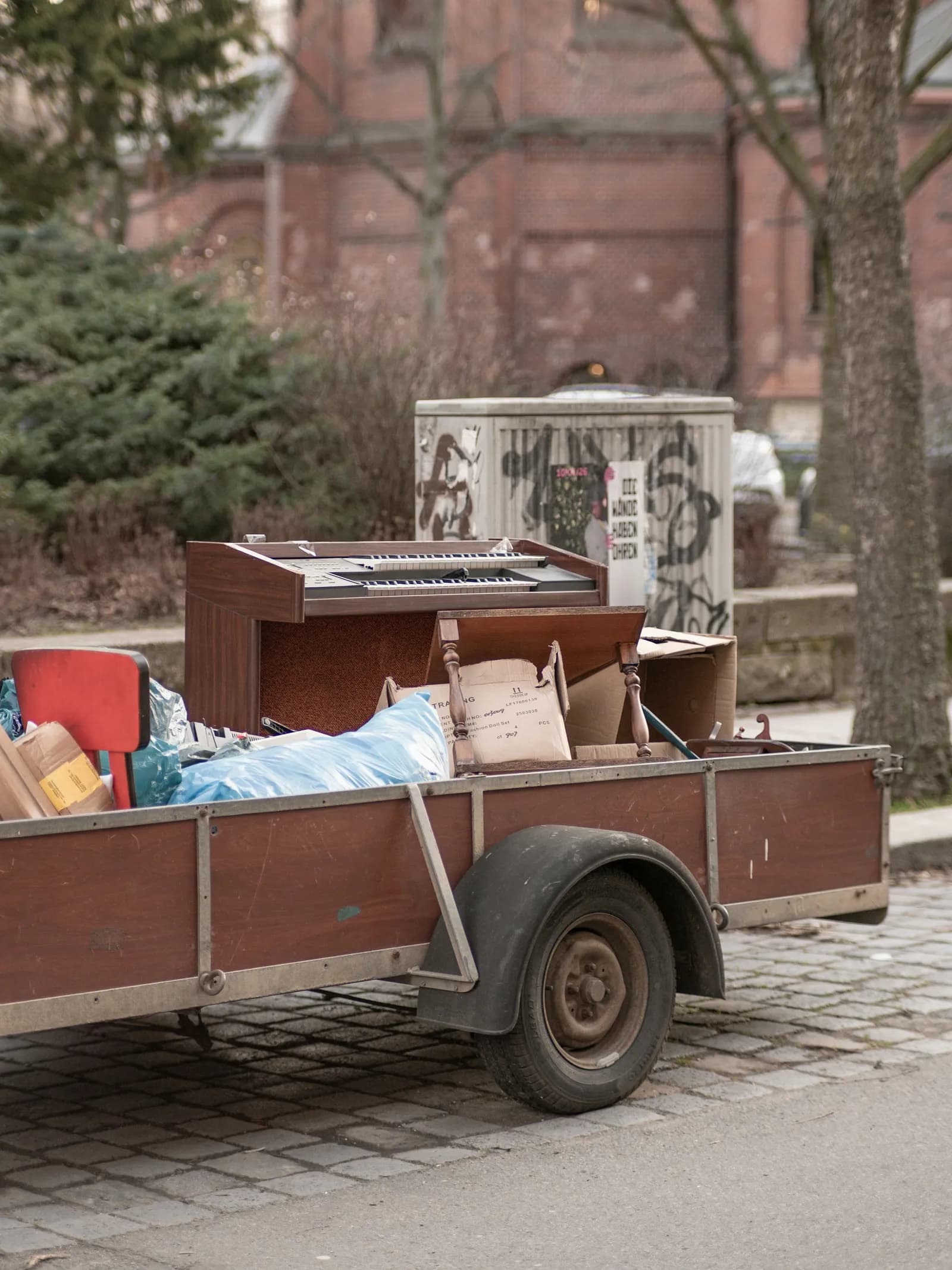 A trailer loaded with an old organ, a chair and bags