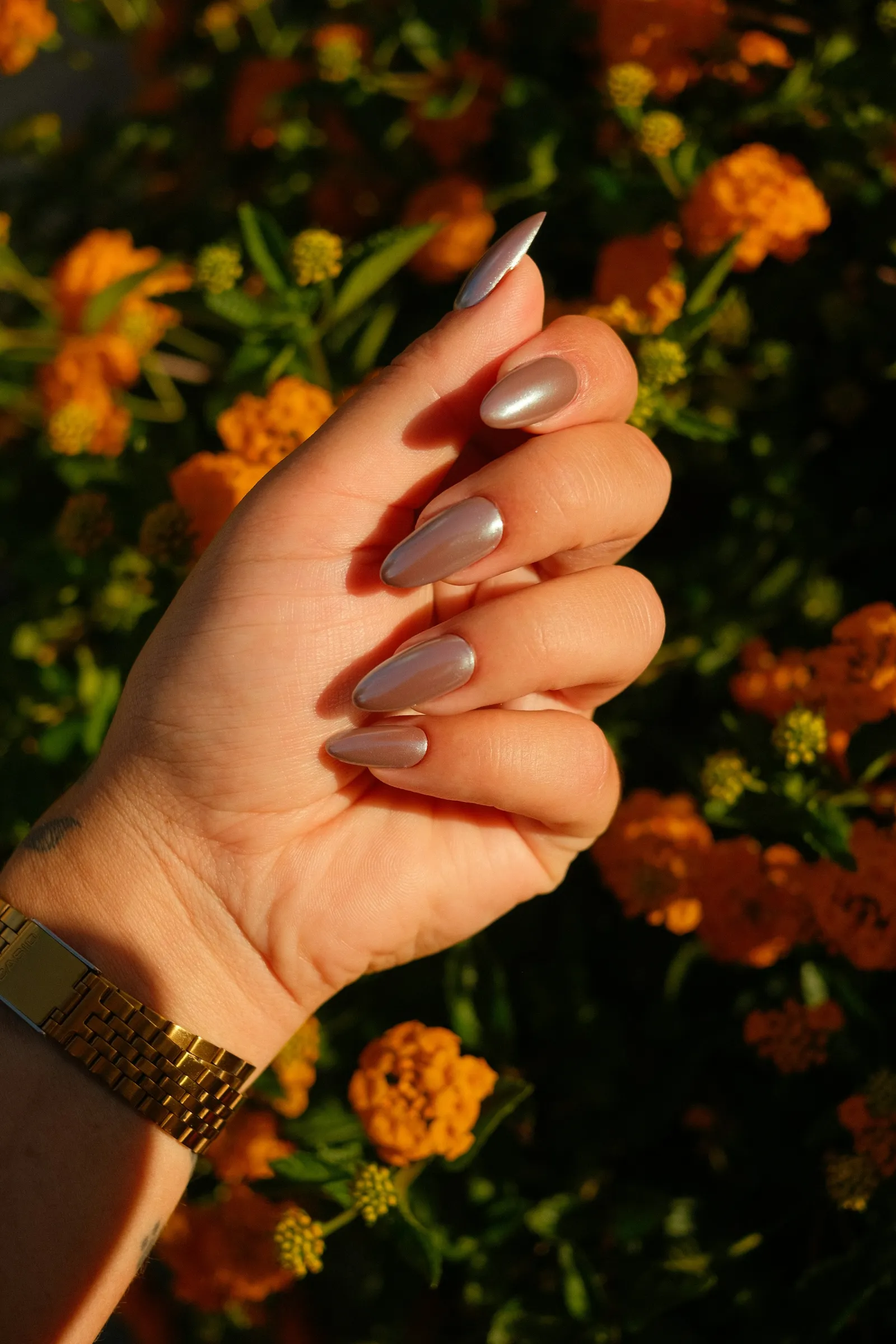 Long almond nails in soft chrome, by orange flowers