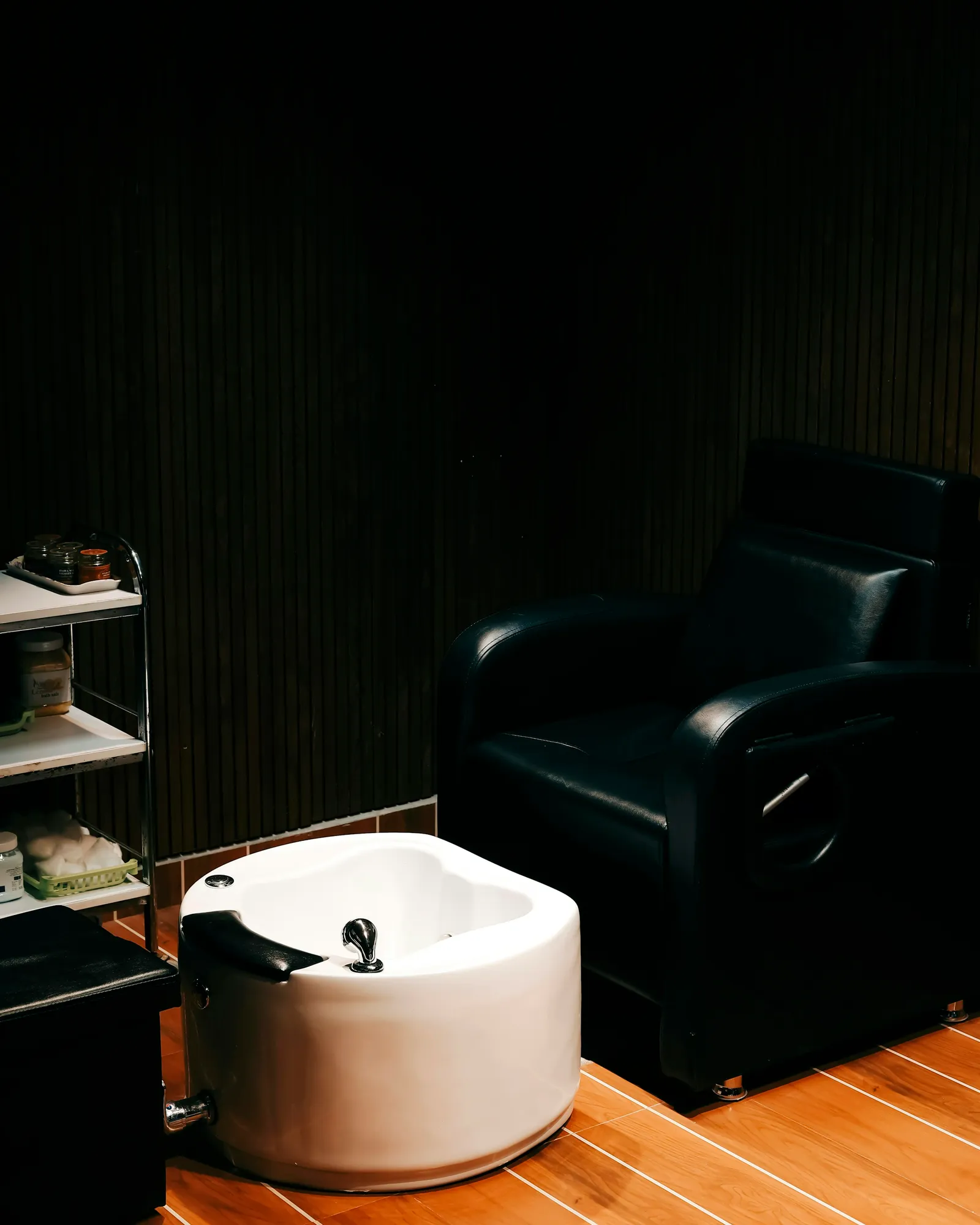 A black pedicure chair with a white foot bath