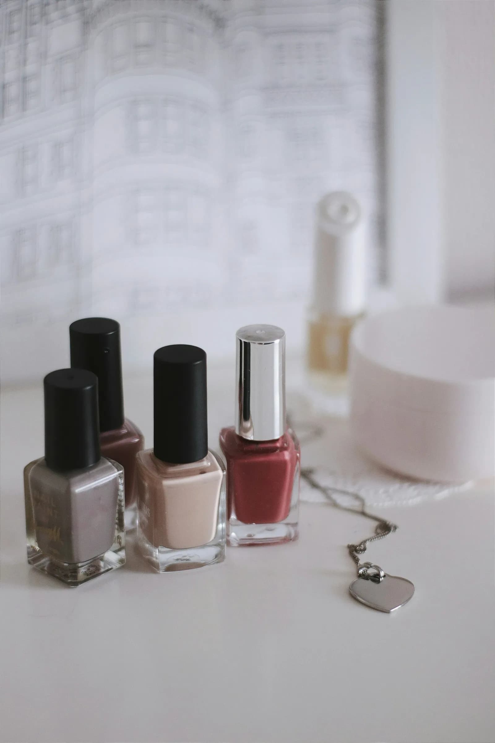 Nail polish bottles in gray, nude and rose on a white table