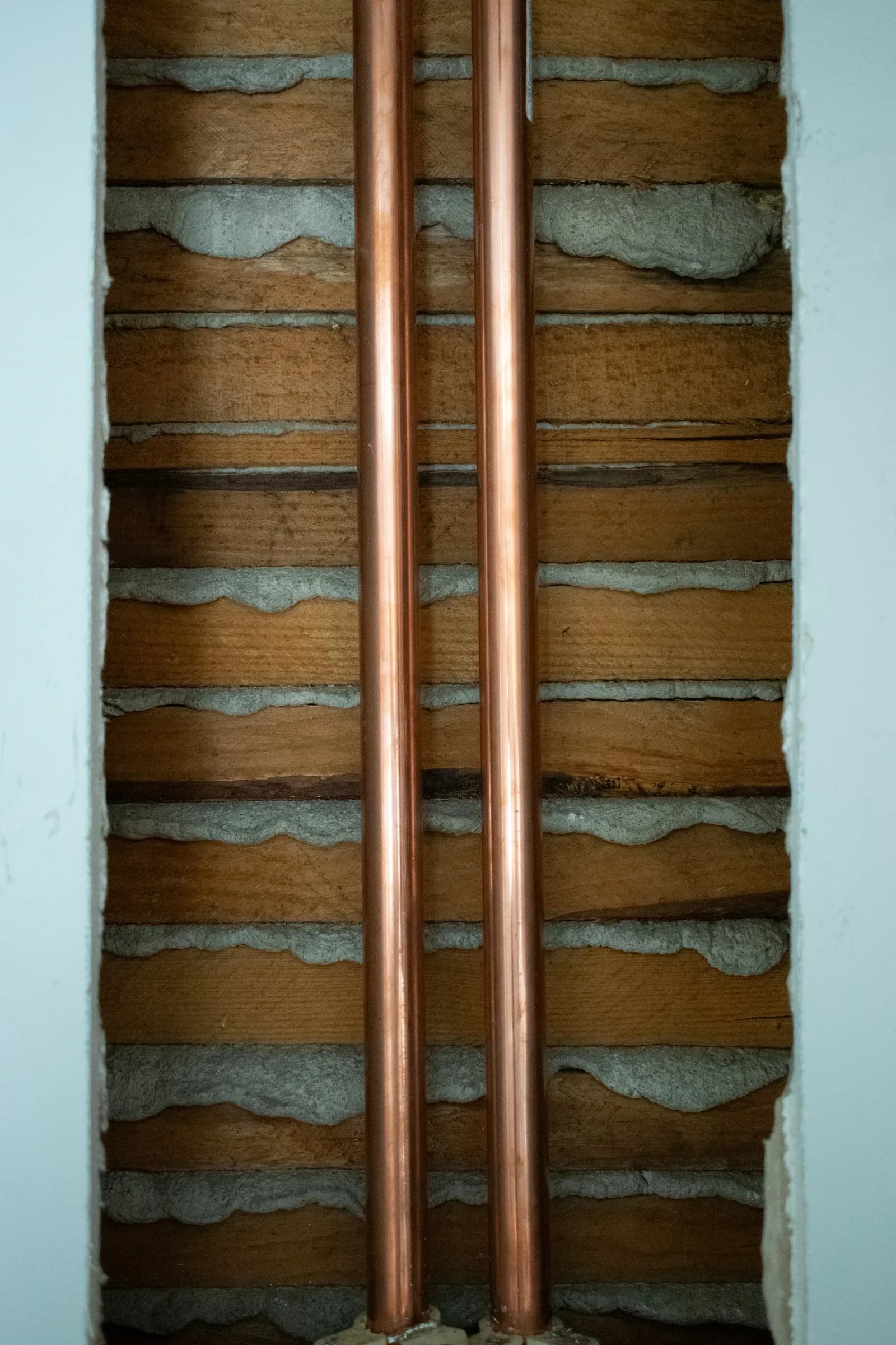 Two copper pipes inside an open wall