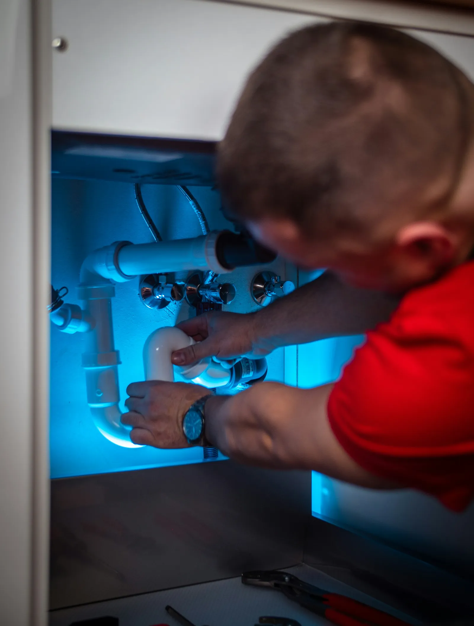 Hands fix the pipes under a bathroom sink