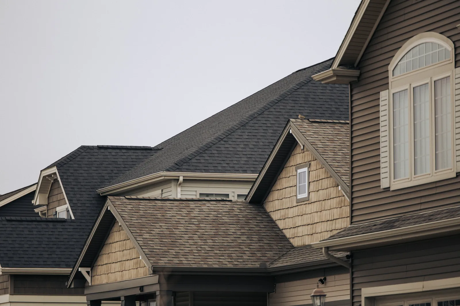 Two story houses with gray and brown shingle roofs