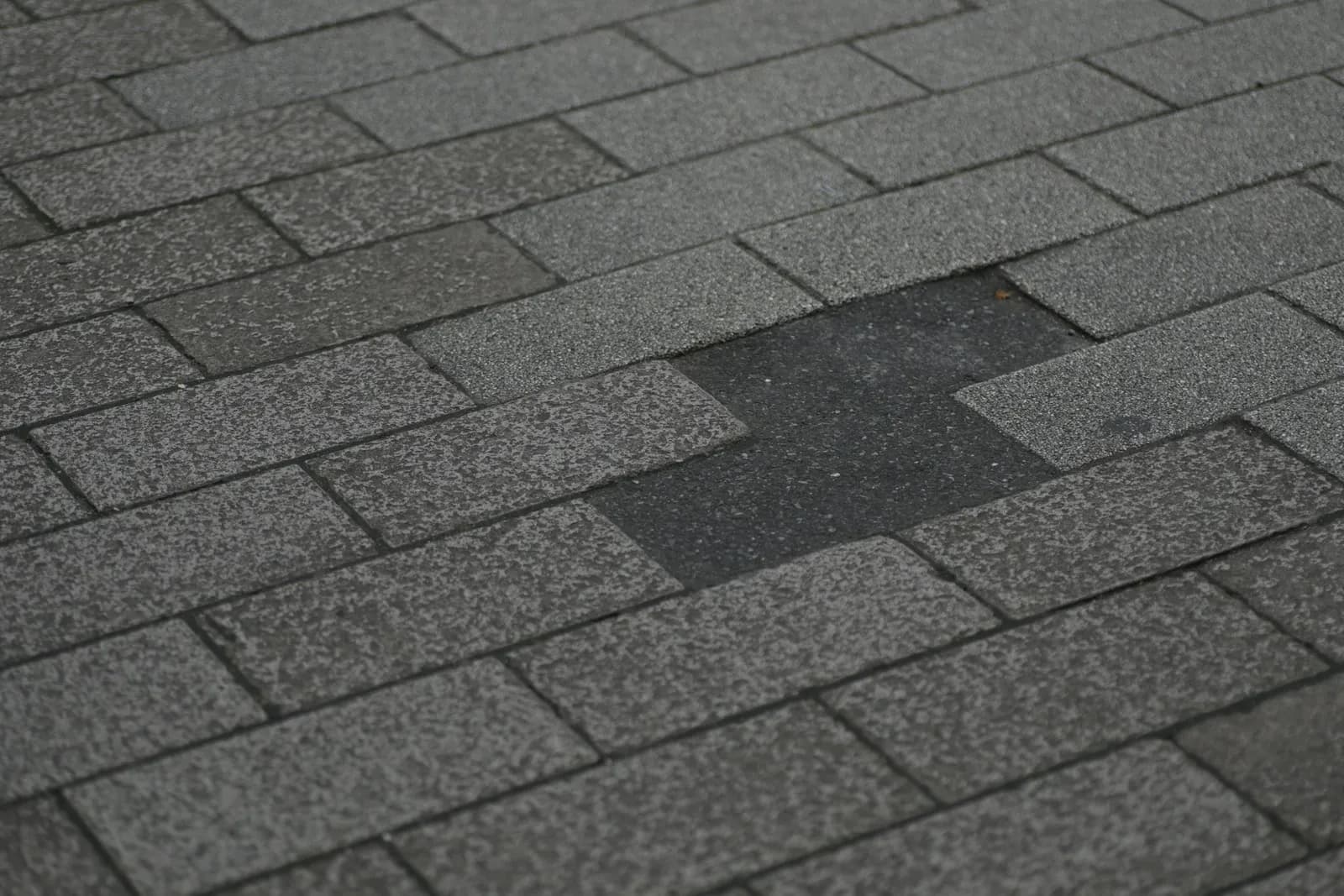 A shingle roof with a patch of shingles blown off