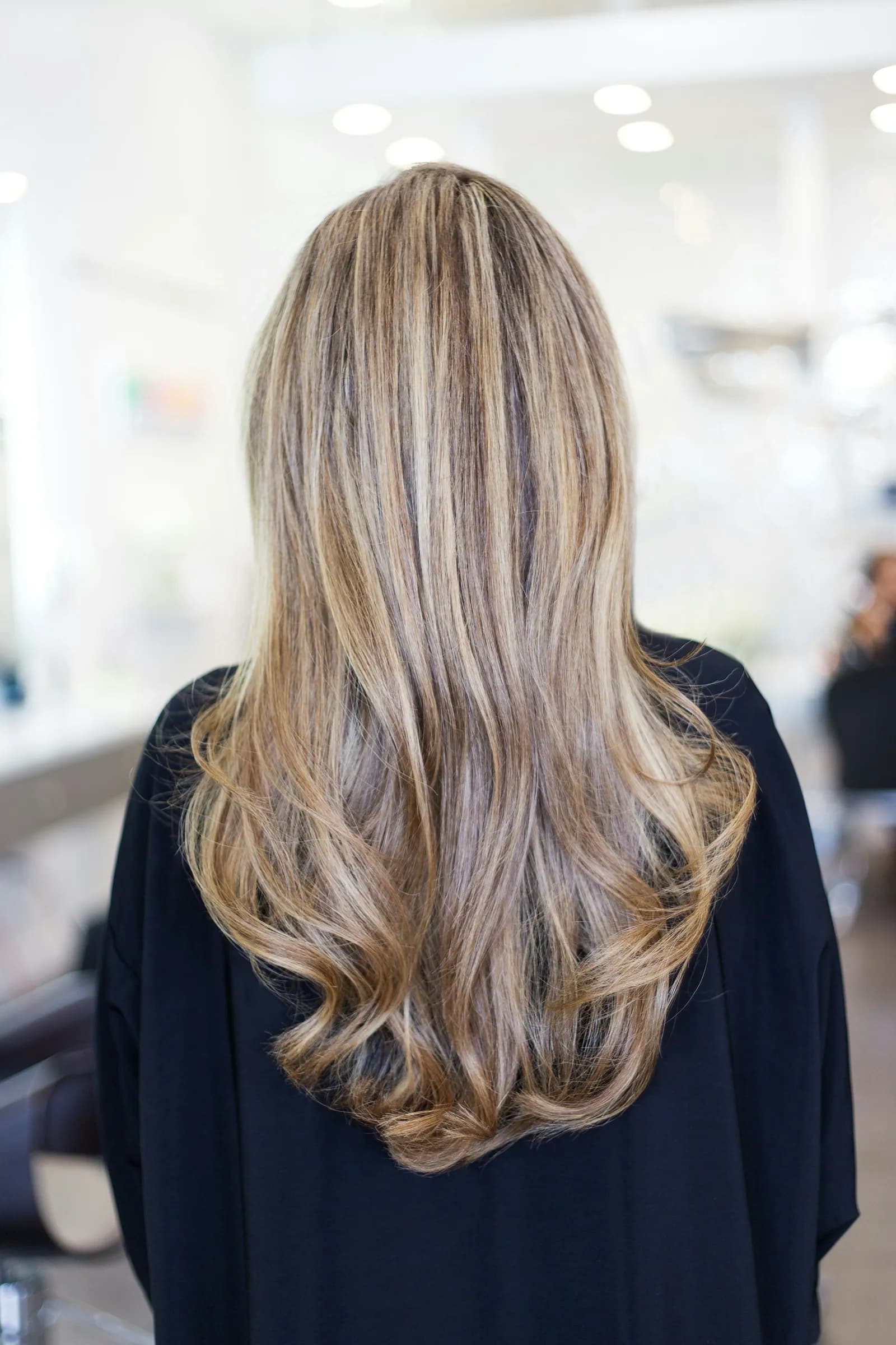 Long blonde balayage, seen from the back in a bright salon