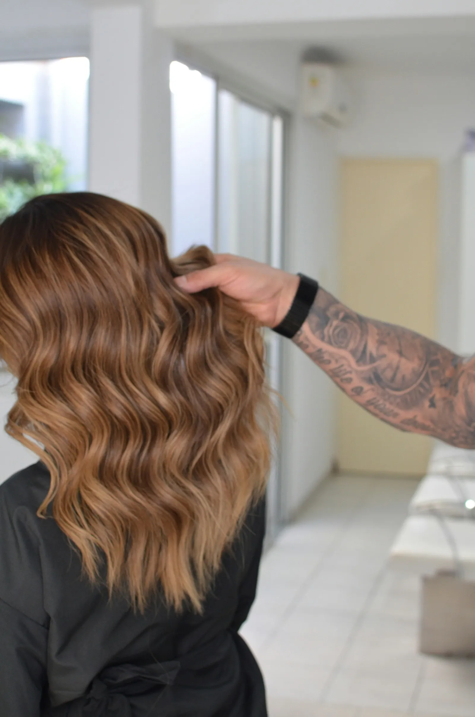 A stylist fluffs soft caramel waves
