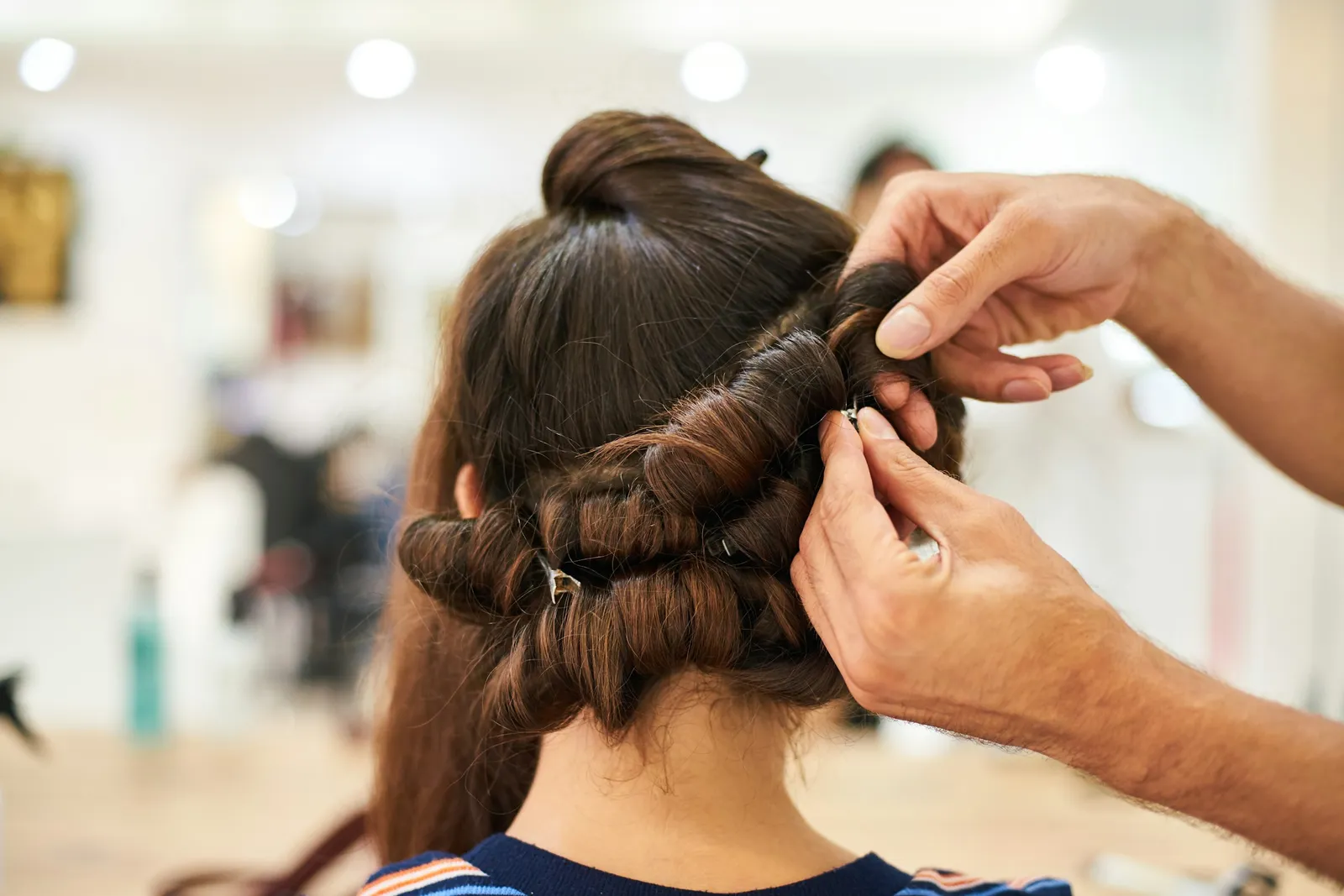 A stylist pins rolled curls into an updo